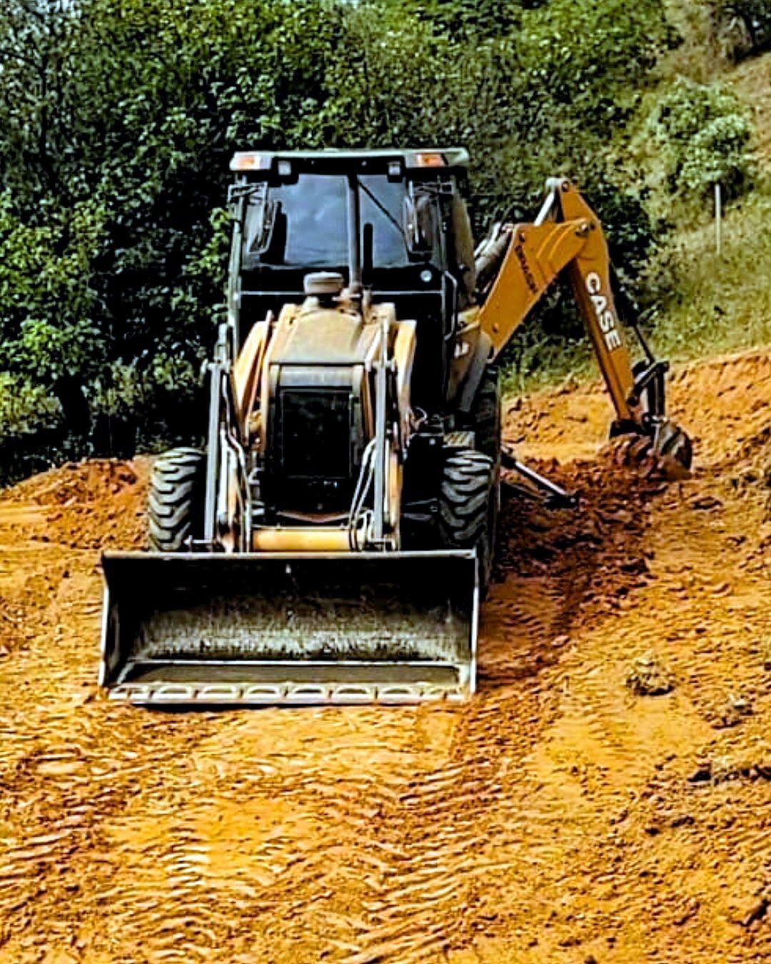 Retroescavadeira Case nivelando acesso de terra em Timóteo MG
