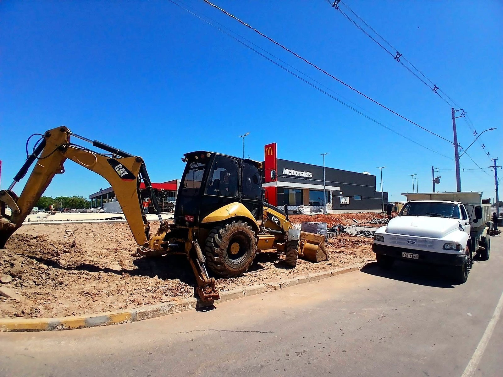 Retroescavadeira CAT 416E e caminhão caçamba em obra de terraplanagem em Canoas/RS