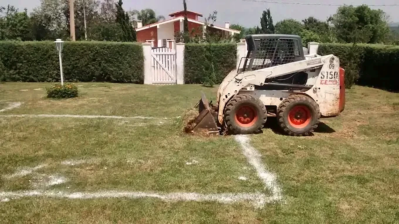 Bobcat S150 começando escavação marcada com cal em gramado de chácara em Boituva, próximo ao portão