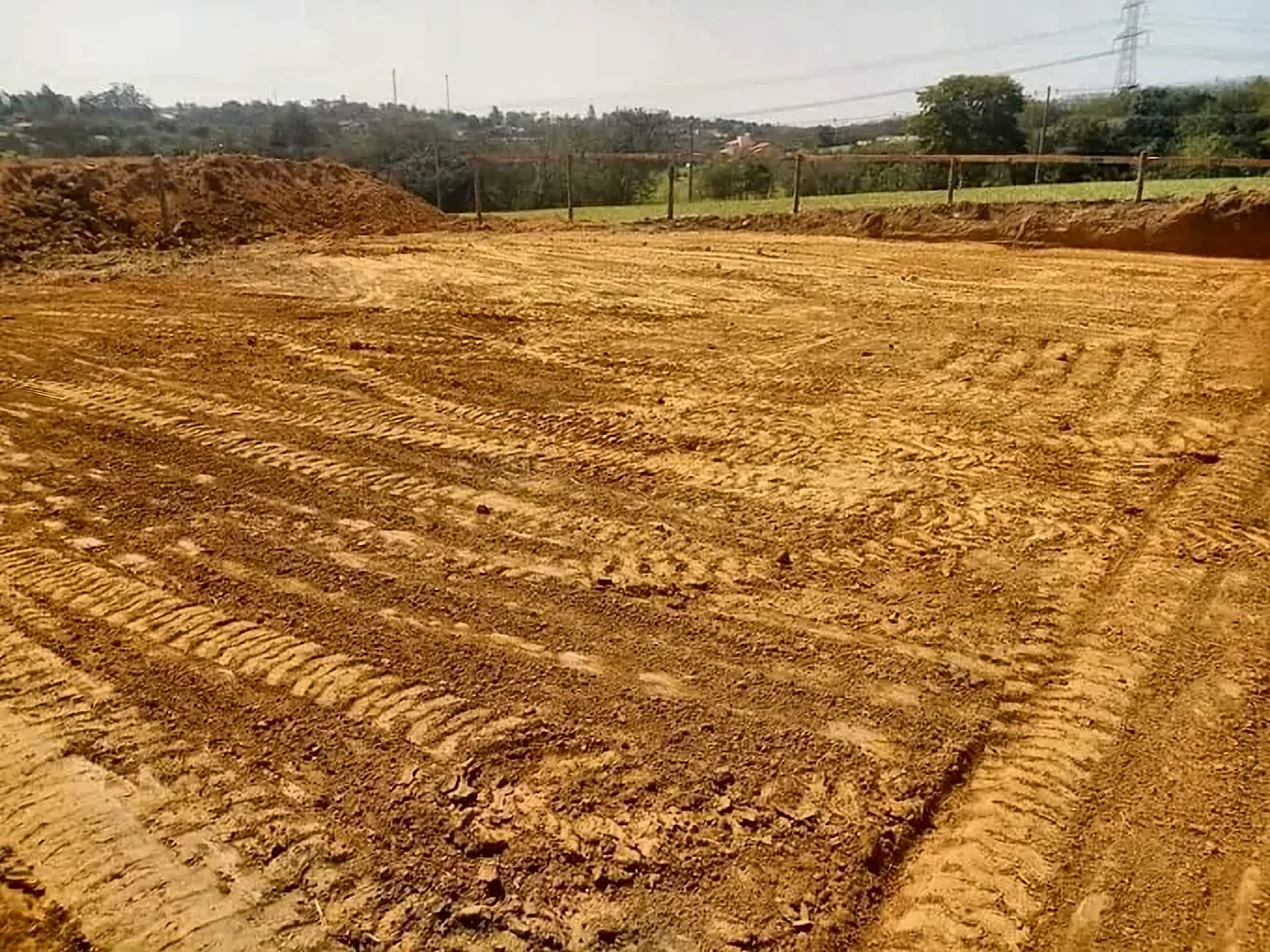 Terreno nivelado e compactado após terraplanagem, com marcas da máquina no solo